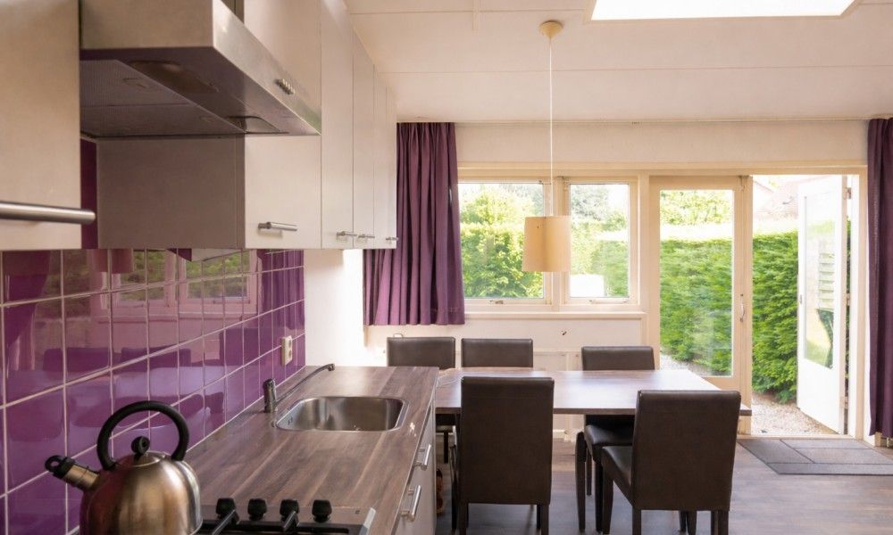 Moderne Kueche und Essbereich in Ferienhaus 3 in einer Reihe in Renesse, Zeeland, mit Blick auf gruenen Garten.