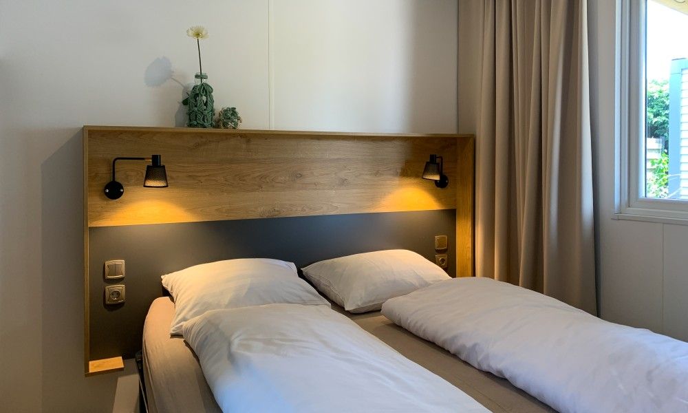 Gezellige slaapkamer in Verseputshofje chalet, Renesse, met comfortabel tweepersoonsbed en sfeervolle verlichting, Zeeland vakantiehuis.