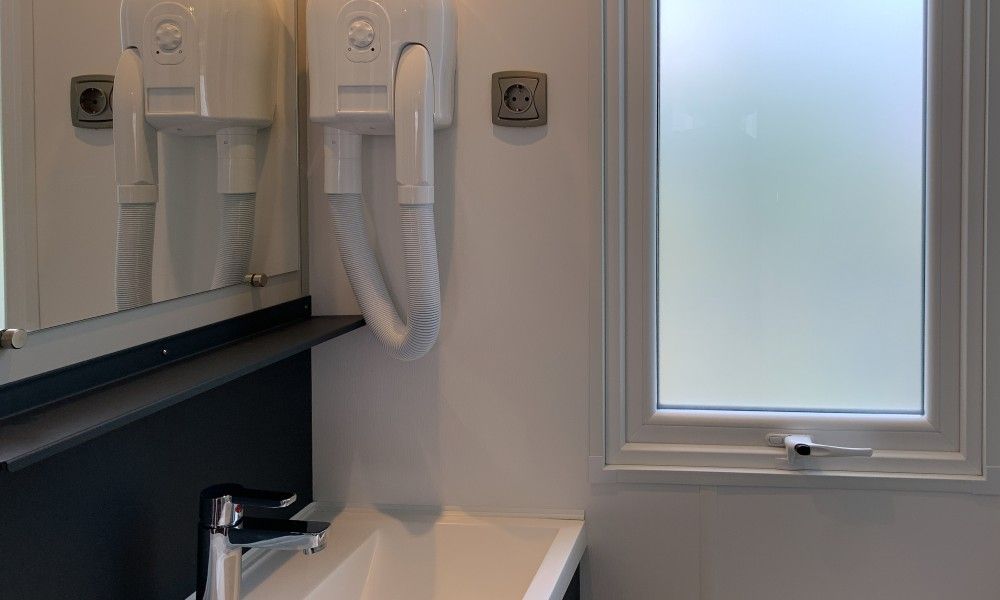 Moderne badkamer van chalet Verseputshofje in Renesse, Zeeland, met stijlvolle wastafel en fohn, ideaal voor een ontspannen verblijf.