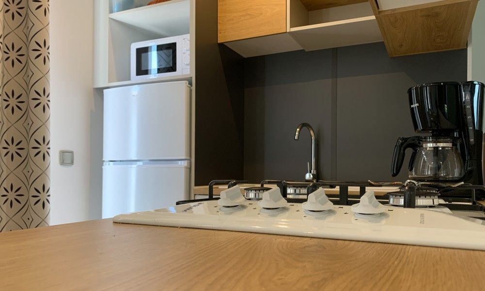 Moderne keuken in chalet Verseputshofje, Renesse, Zeeland met fornuis, koelkast en koffiezetapparaat voor een comfortabel verblijf.