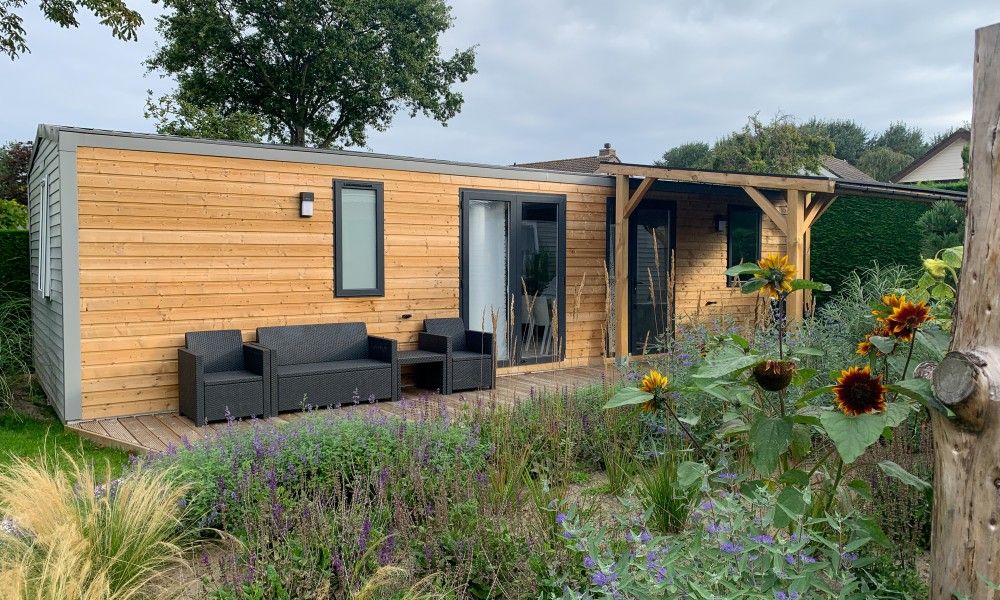 Verseputshofje chalet in Renesse, Schouwen-Duiveland, met houten terras en kleurrijke tuin, ideaal voor een ontspannen vakantie in Zeeland.