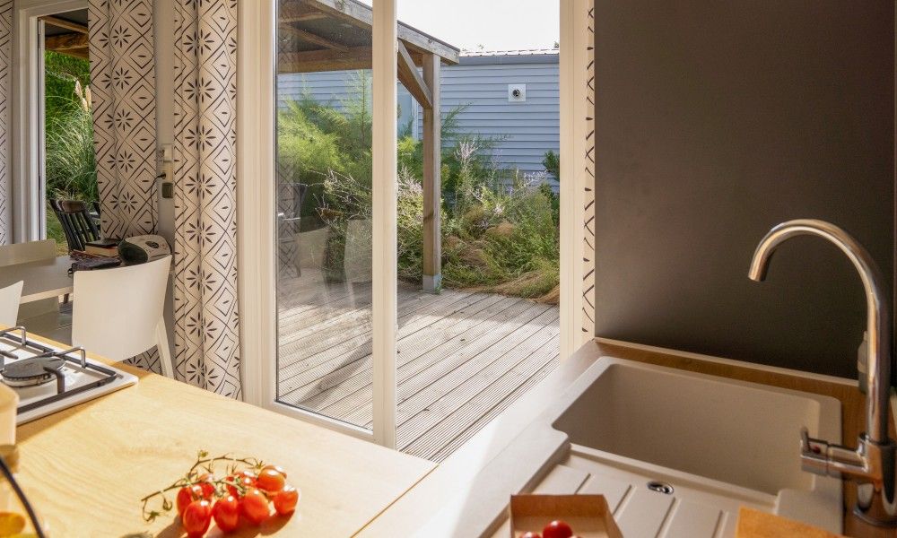 Verseputshofje chalet in Renesse, Zeeland met uitzicht op terras vanuit de keuken, omgeven door groene natuur en rustgevende omgeving.