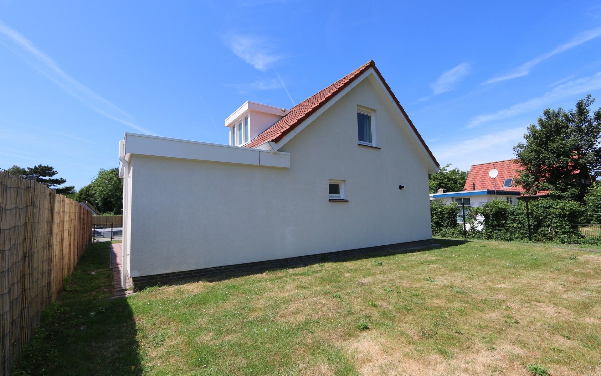 Side view of Holiday home Horizon 95 in Zeeland, surrounded by a green garden for privacy and tranquility.