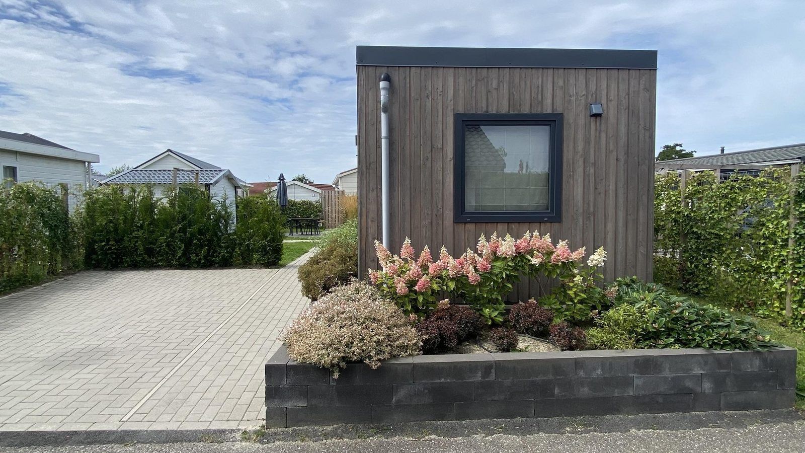 Zijaanzicht van VZ1016 Vakantiechalet in Sint-Annaland met bloembed, Tholen, Zeeland.