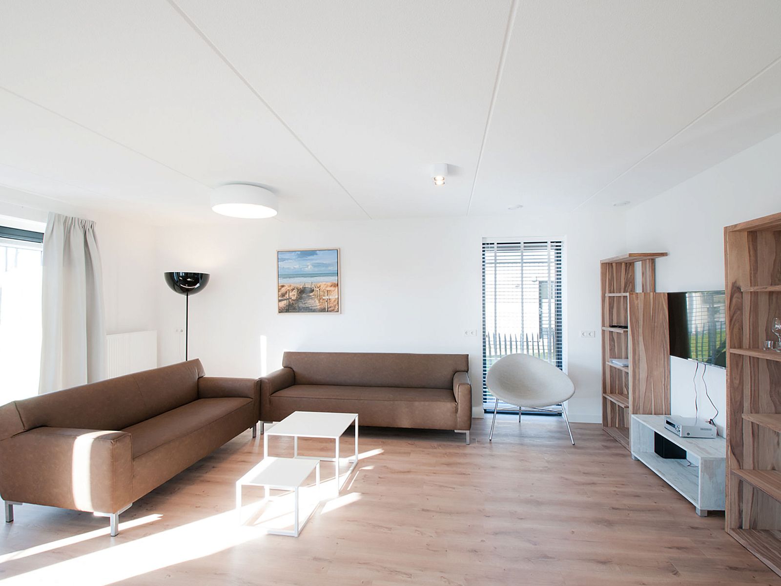 Moderne woonkamer in Vakantiehuis Oesterdam Resort, Tholen, Zeeland, met comfortabele banken en veel natuurlijk licht.