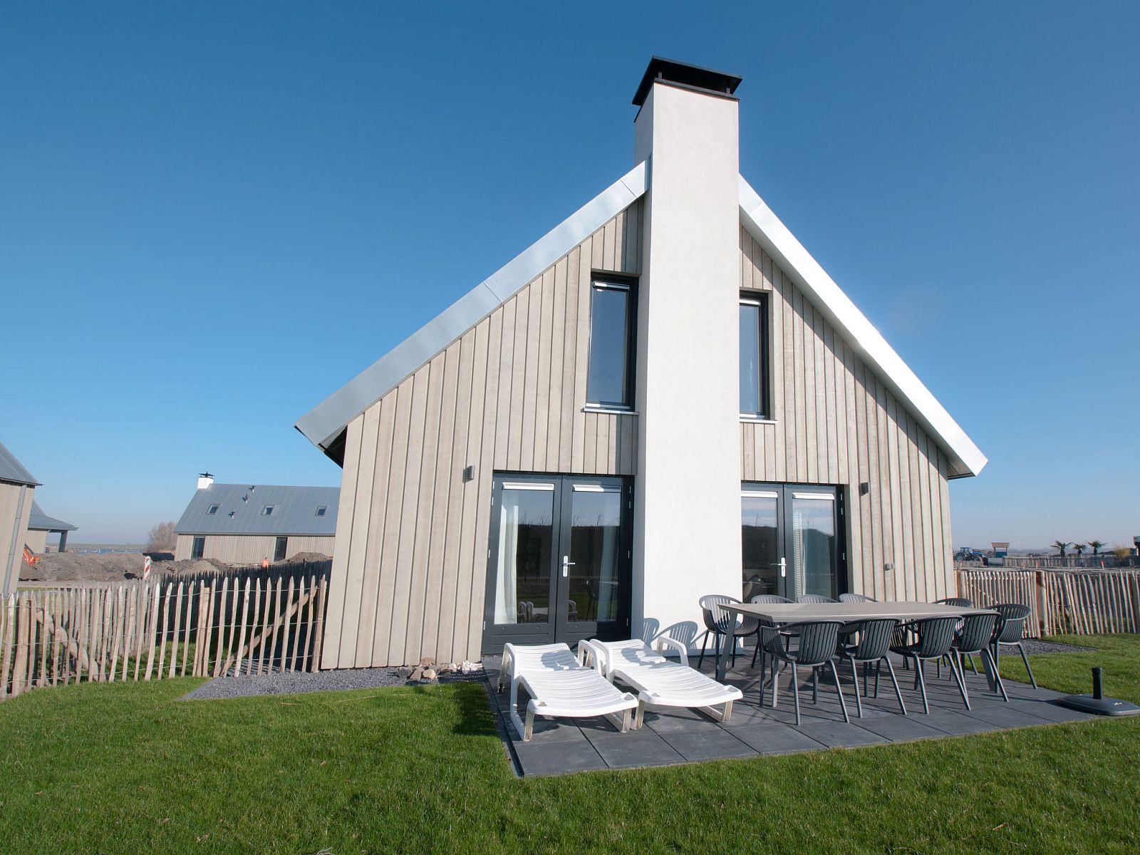 Terras met ligstoelen bij Vakantiehuis Oesterdam Resort in Tholen, Zeeland, ideaal voor zonnige dagen.