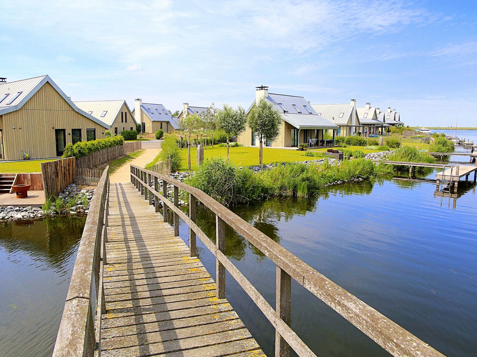 Houten brug over het water bij Vakantiehuis Oesterdam Resort in Tholen, Zeeland, met uitzicht op vakantiehuizen.