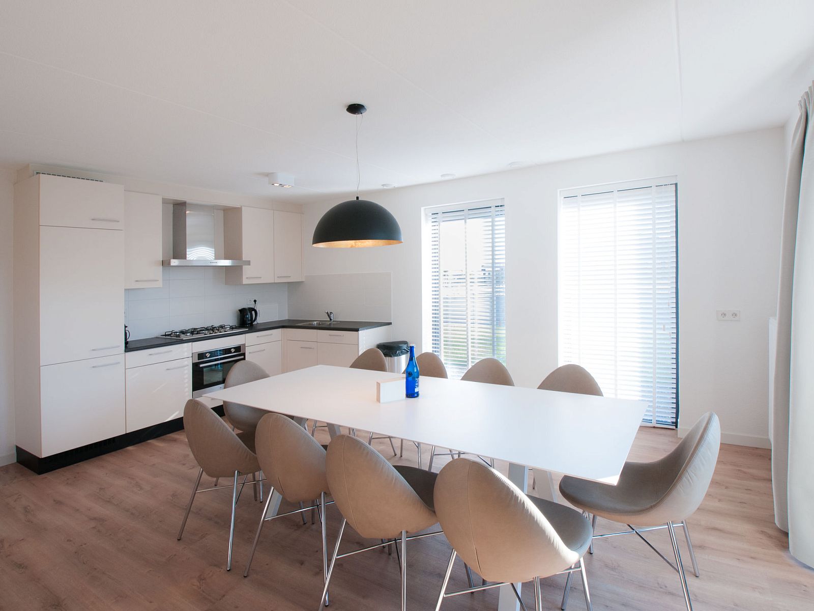 Eetkamer en keuken in Vakantiehuis Oesterdam Resort, Tholen, Zeeland, met moderne inrichting en veel licht.