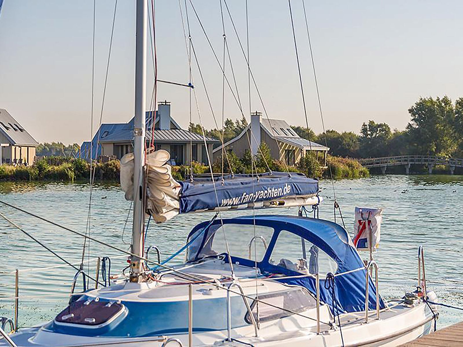 Zeilboot voor Vakantiehuis Oesterdam Resort in Tholen, Zeeland, met vakantiehuizen op de achtergrond.
