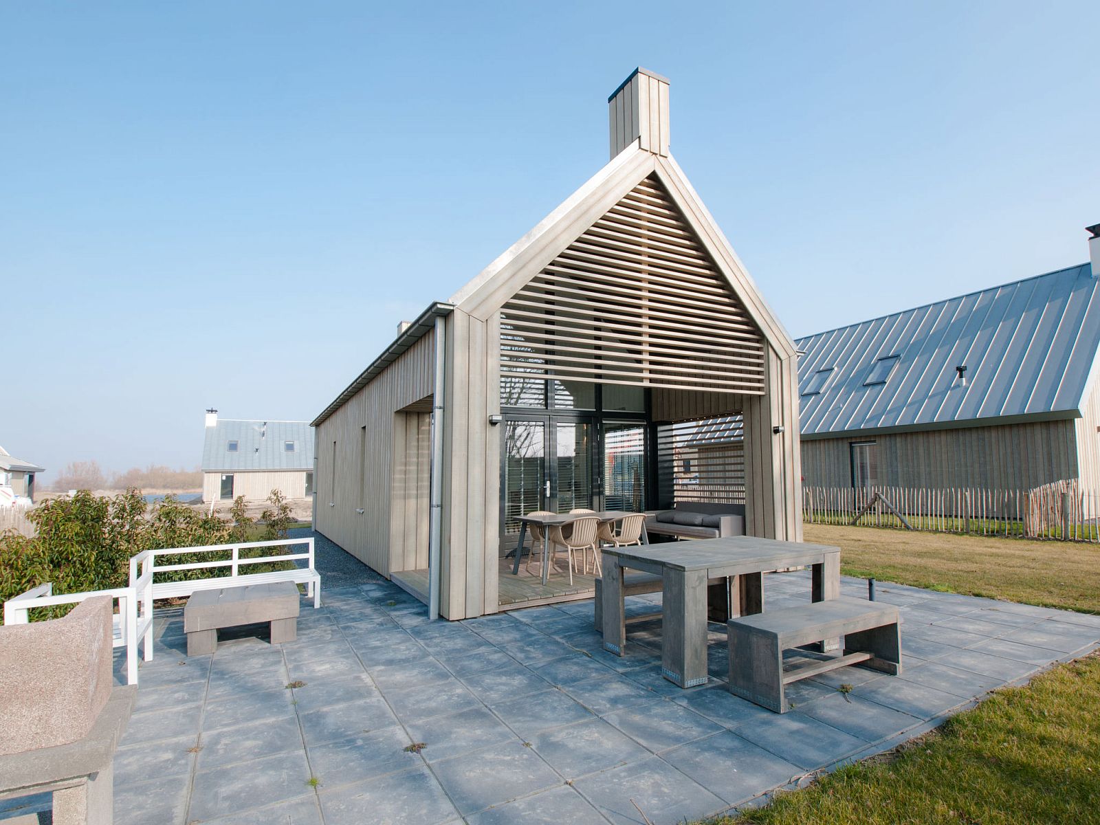 Geraeumige Terrasse des Ferienhauses Oesterdam Resort in Tholen, Zeeland mit Holzmoebeln.