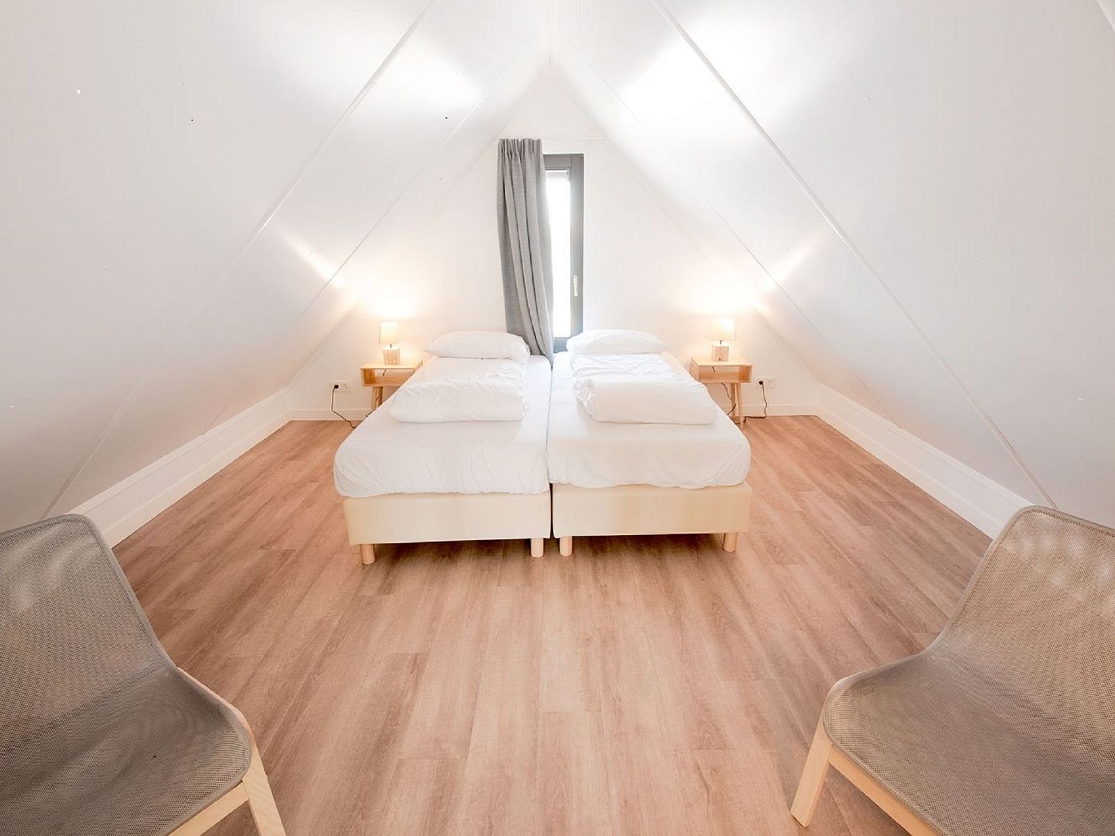 Helles Schlafzimmer im Dachgeschoss des Ferienhauses Oesterdam Resort, Tholen, Zeeland mit Holzboden.