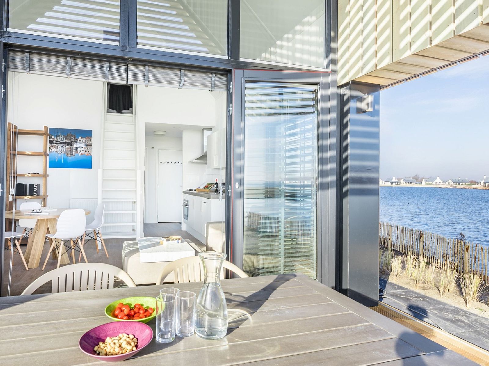 Esstisch auf der Terrasse des Ferienhauses Oesterdam Resort in Tholen, Zeeland, mit Blick auf den See.