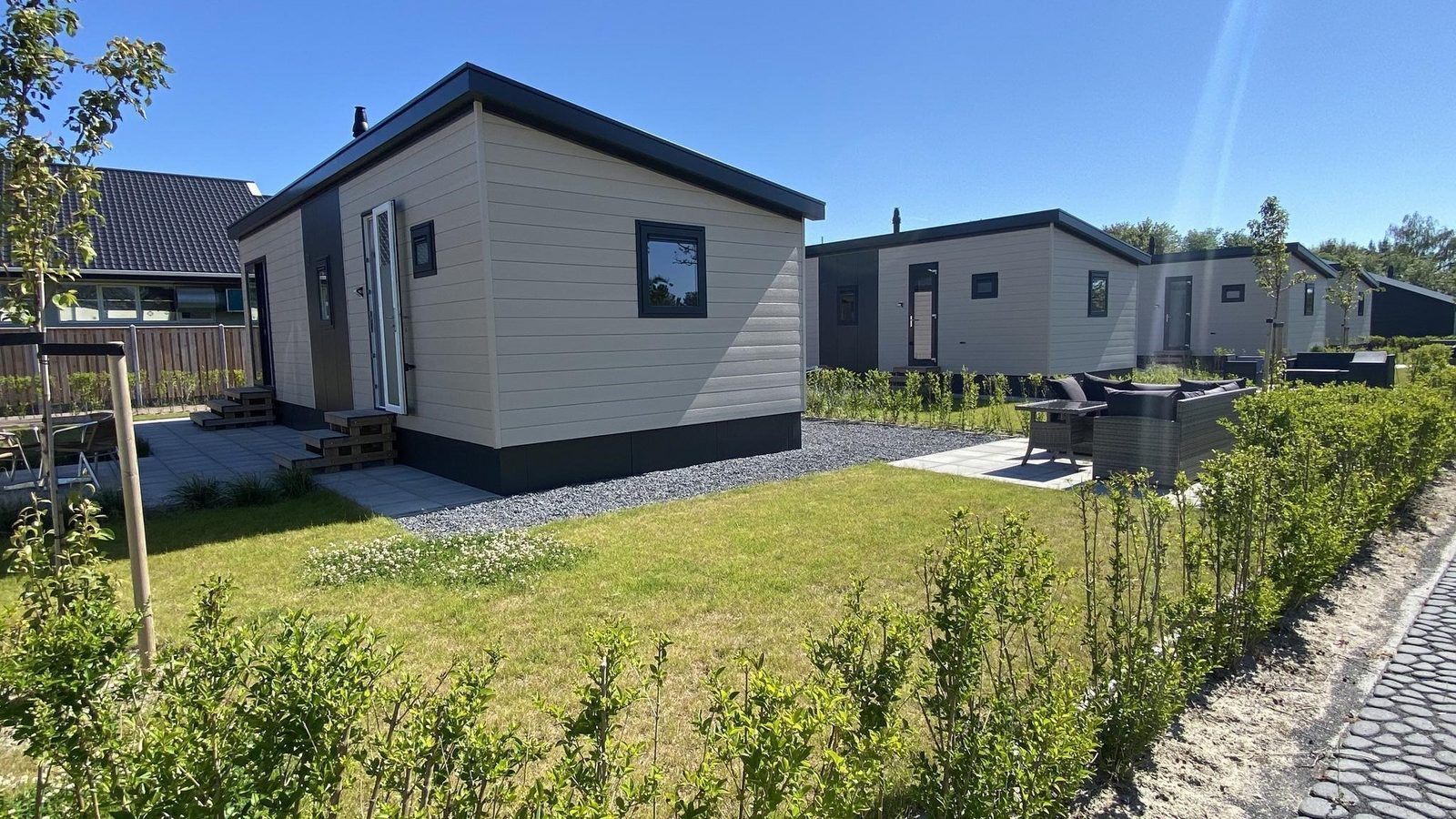 Sommerlicher Aussenbereich des VZ873 Ferienchalets in Scherpenisse mit gruener Umgebung in Tholen, Zeeland.