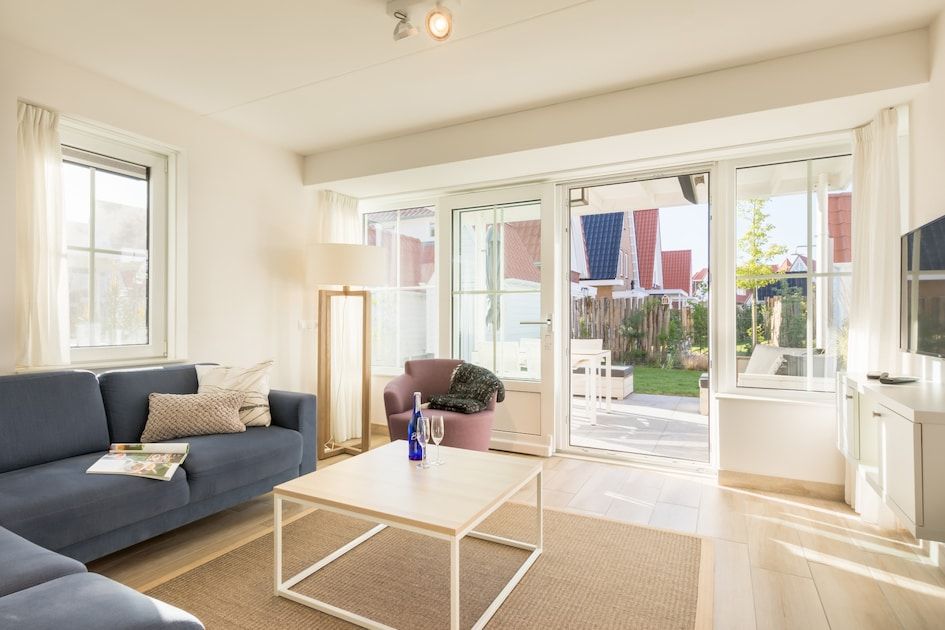 Lichte woonkamer van Banckert Luxe Outdoor 4 vakantiehuis in Koudekerke, Walcheren, met uitzicht op terras en tuin.