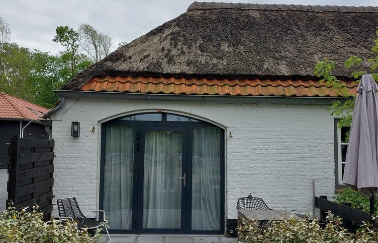 Charming cottage in Koudekerke, Walcheren, Zeeland with thatched roof and cozy outdoor area for a relaxing stay.