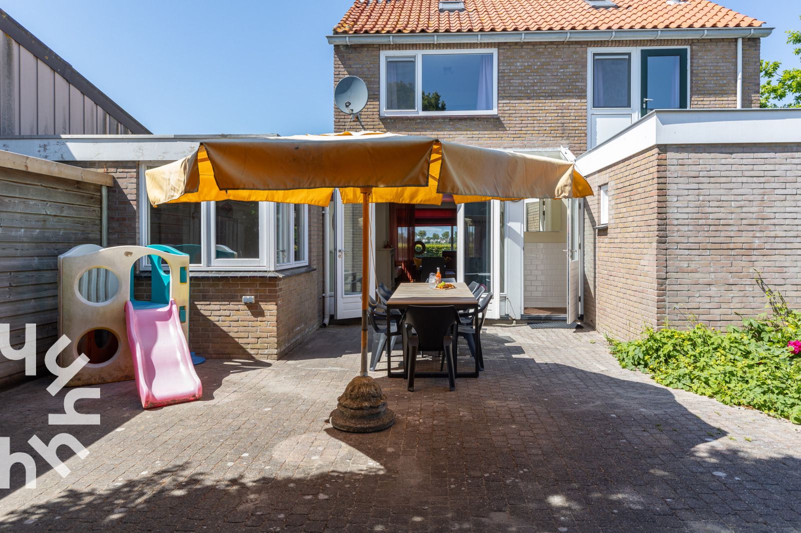 Geraeumige Terrasse des Ferienhauses ZE142 in Koudekerke, Walcheren mit grossem Sonnenschirm und Sitzgelegenheit.