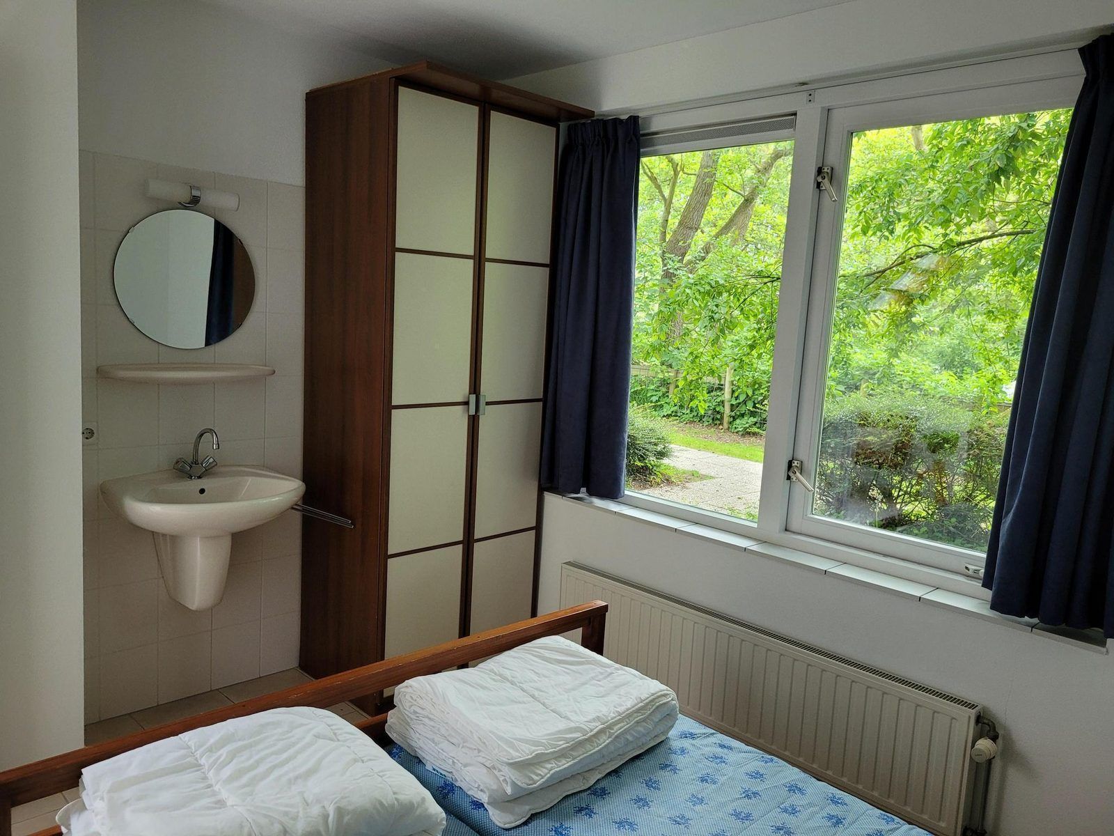 Slaapkamer met wastafel en uitzicht op tuin in VZ2330 Vakantiehuis Oostkapelle, Walcheren, Zeeland.