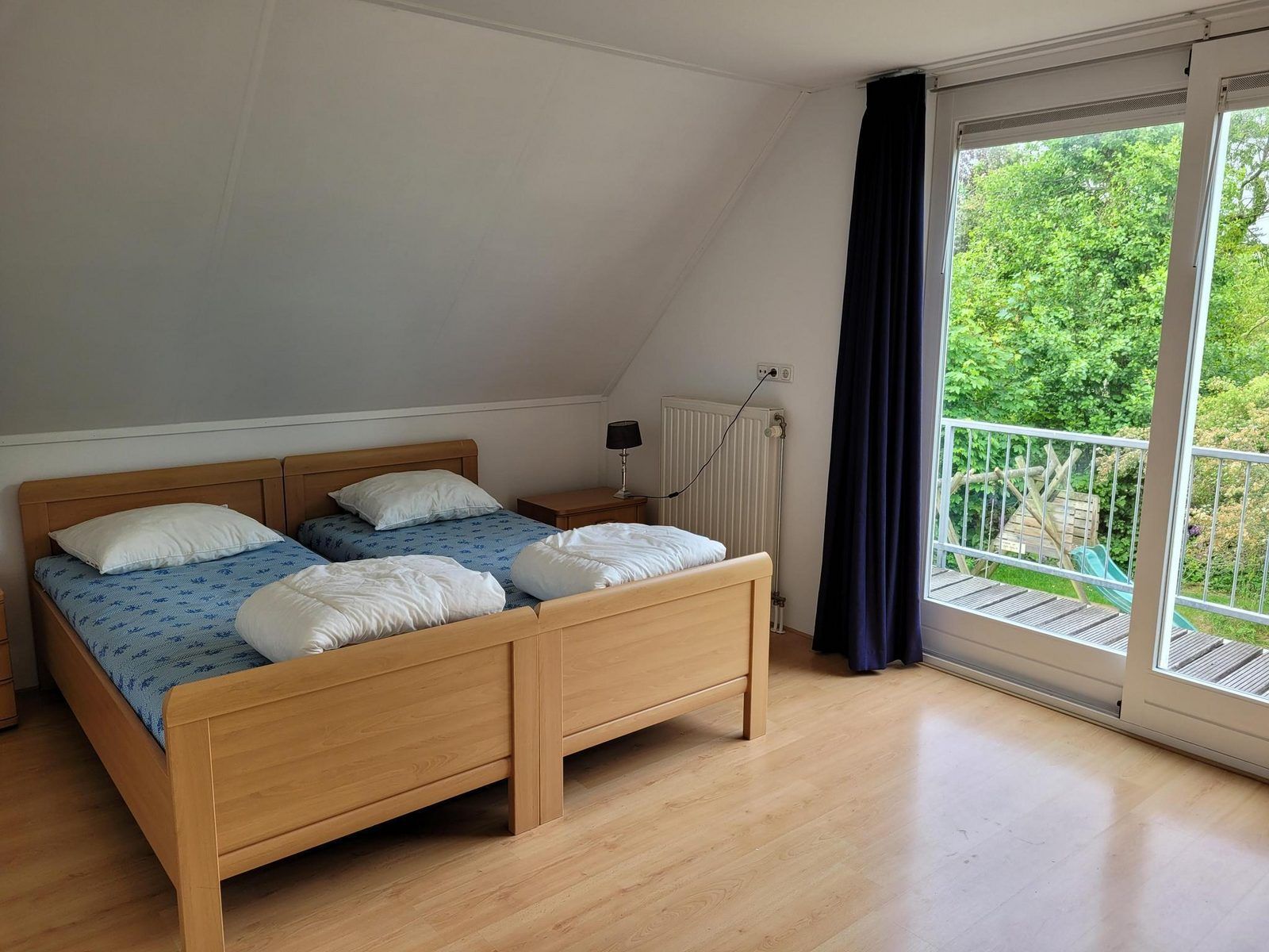 Slaapkamer met balkon en uitzicht op tuin in VZ2330 Vakantiehuis Oostkapelle, Walcheren, Zeeland.