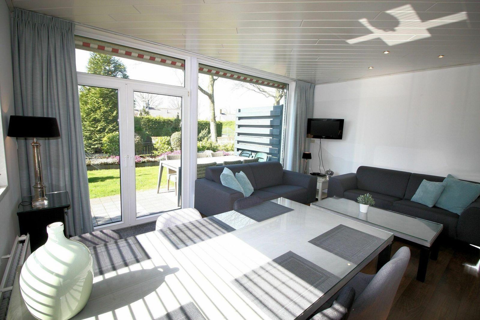 Lichte woonkamer in VZ986 Vakantiebungalow in Oostkapelle met uitzicht op de tuin in Walcheren, Zeeland.