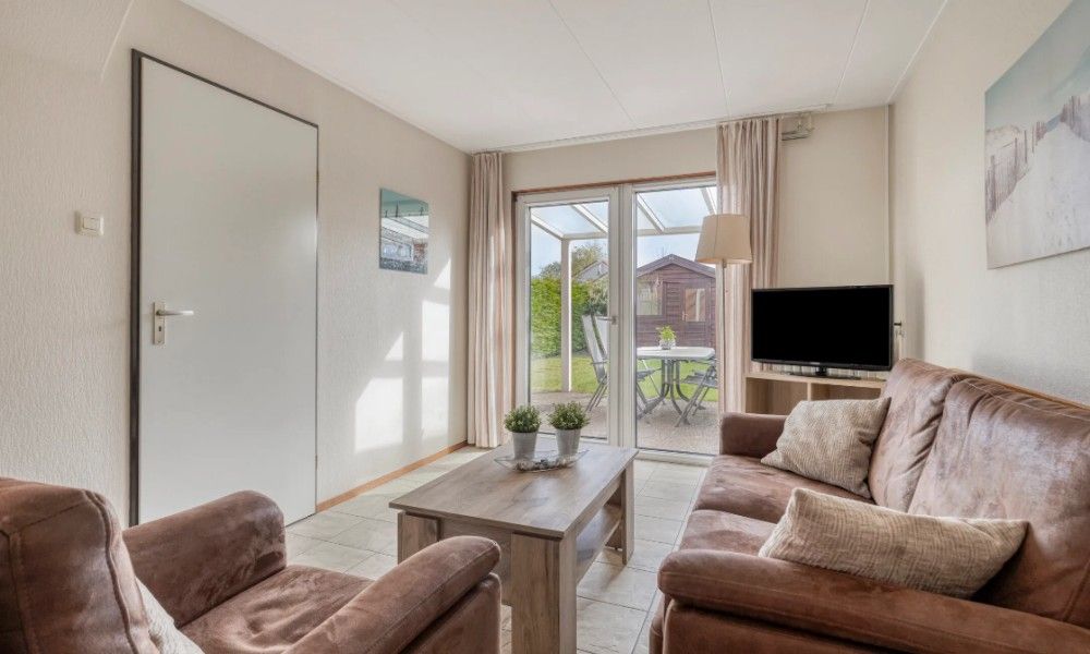 Gezellige woonkamer in Vakantiewoning Oostkapelle, Walcheren, met comfortabele zithoek en uitzicht op de tuin nabij het strand van Zeeland.