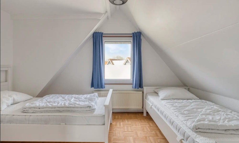 Sfeervolle slaapkamer in Vakantiewoning Oostkapelle, Walcheren, met twee bedden en uitzicht op de omgeving, op 800 meter van het strand.
