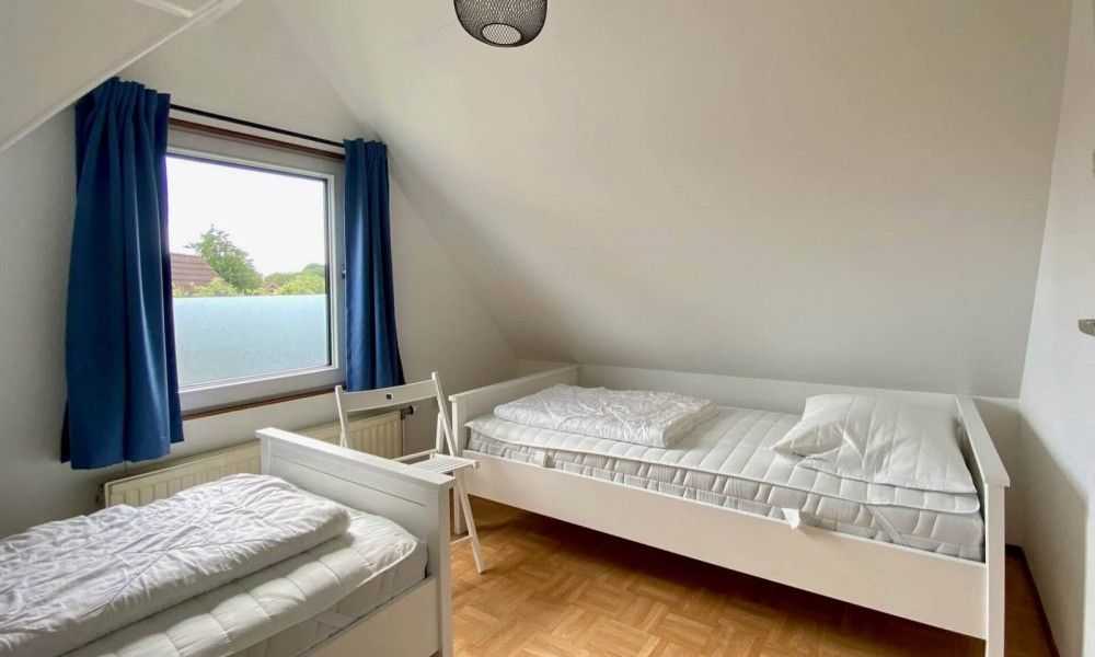 Sfeervolle slaapkamer in Vakantiewoning Oostkapelle, Walcheren, Zeeland, met comfortabele bedden en uitzicht op de groene omgeving.