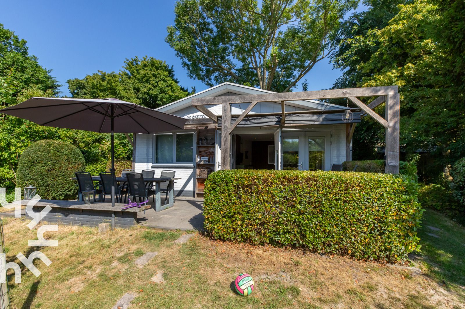 Veranda of vacation home ZE721 in Oostkapelle, Walcheren, with garden furniture and parasol.