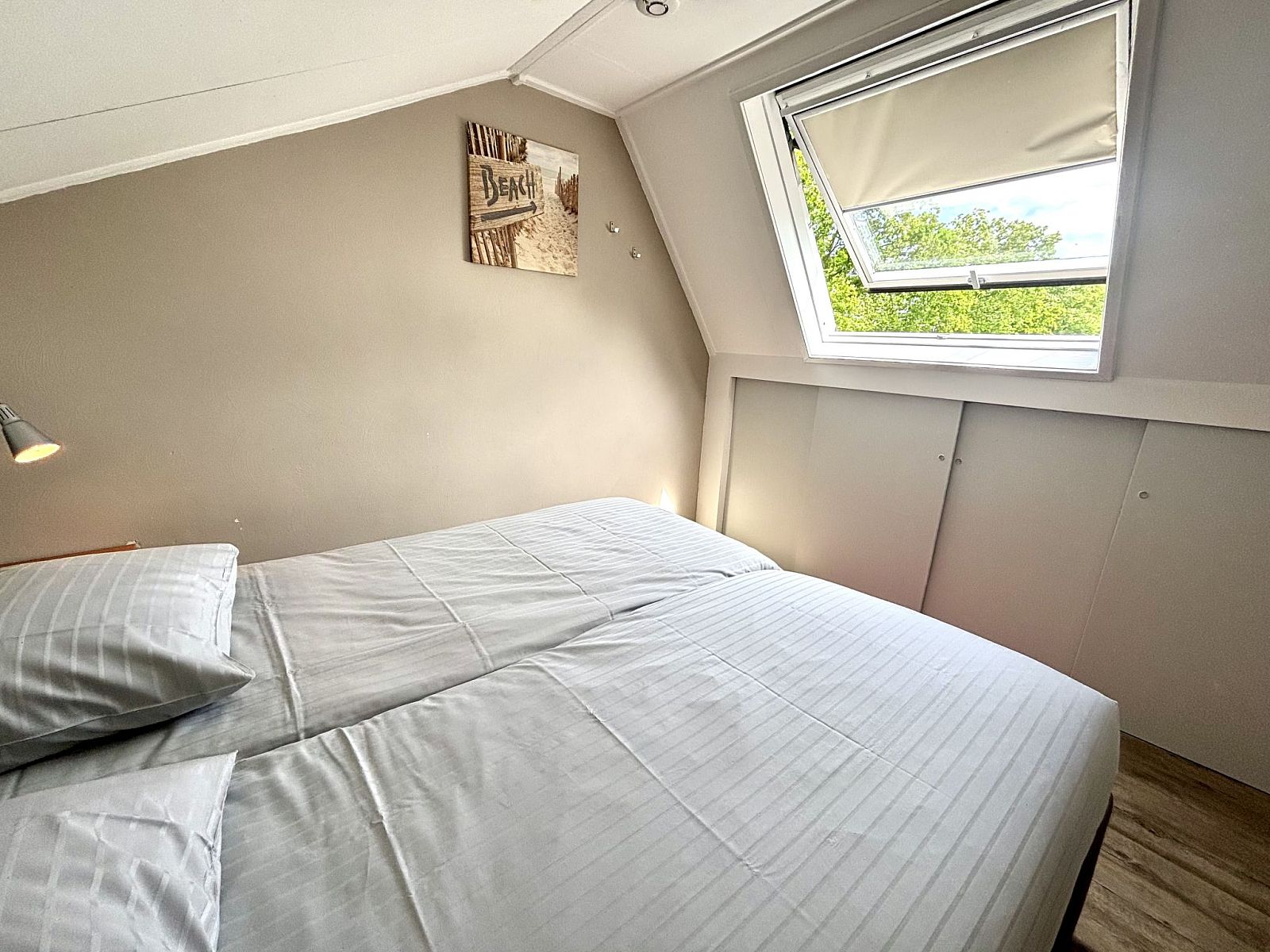 Slaapkamer met groot raam in Appartement Boszicht 3, Oostkapelle, Walcheren, Zeeland biedt veel licht.