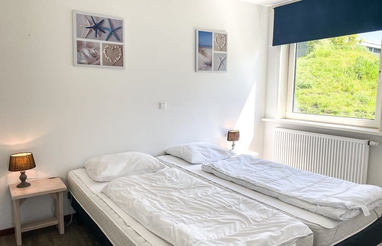 Slaapkamer met dubbel bed in Vakantiehuisje in Oostkapelle, Walcheren, met uitzicht op de tuin.