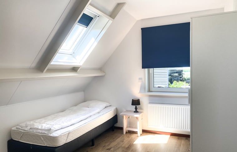 Gezellige slaapkamer in Vakantiehuisje in Oostkapelle, Walcheren, met houten vloer en bed.