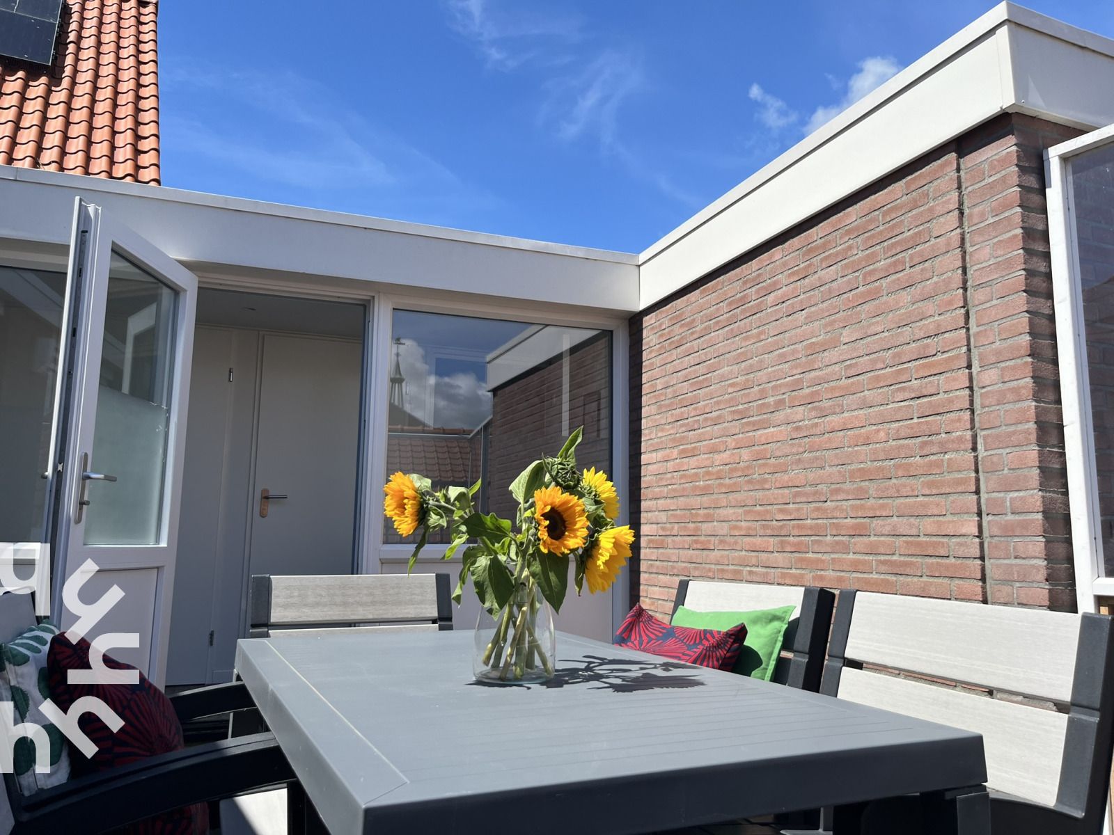 Terrace of vacation home ZE927 in Westkapelle, Walcheren, with sunflowers and blue sky.