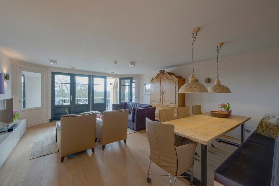 Eetkamer en zitgedeelte van Champagne Wellness 6 appartement in Domburg met uitzicht op de natuur.