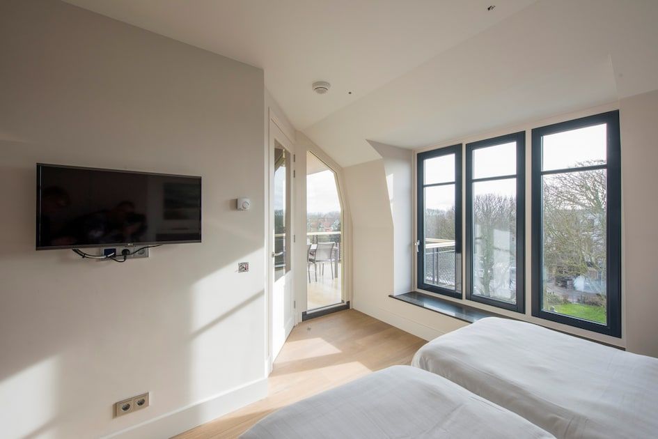 Slaapkamer in Champagne Wellness 6 in Domburg, Zeeland met grote ramen en uitzicht op de omgeving.