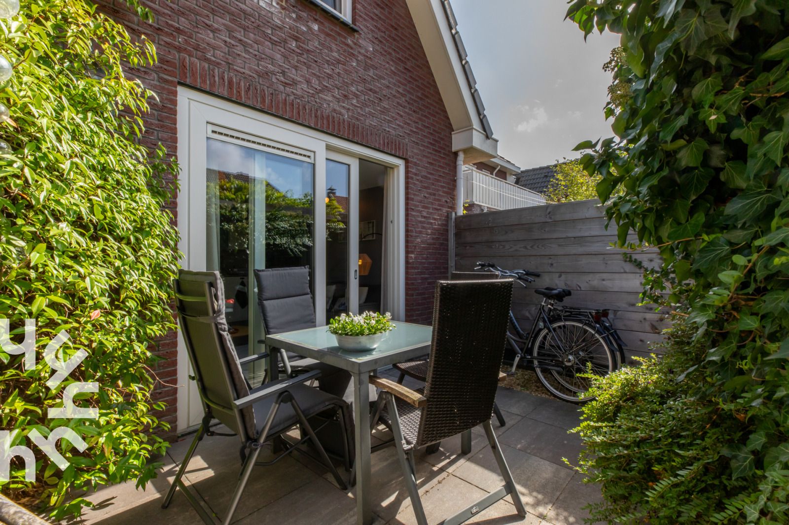 Gezellig terras van vakantiehuis ZE1594 in Domburg, Walcheren, Zeeland met groene planten en eettafel.