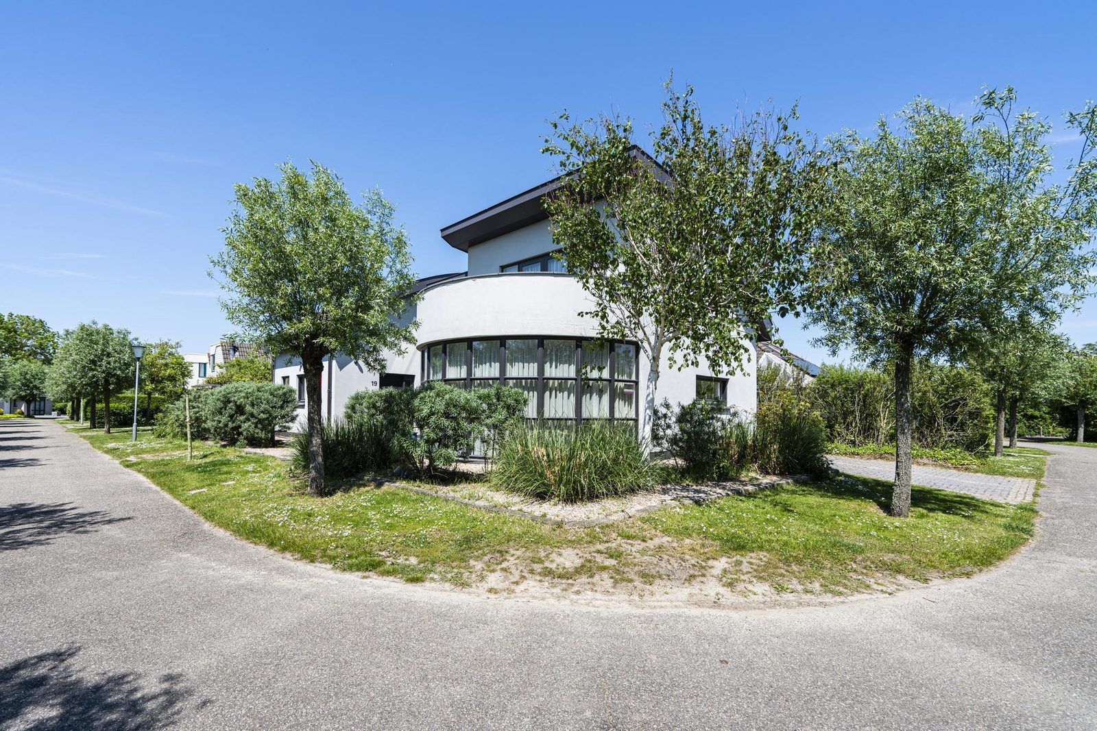 Seitenansicht der Luxus-Ferienvilla VZ908 in Vlissingen, umgeben von Baeumen in Walcheren, Zeeland.