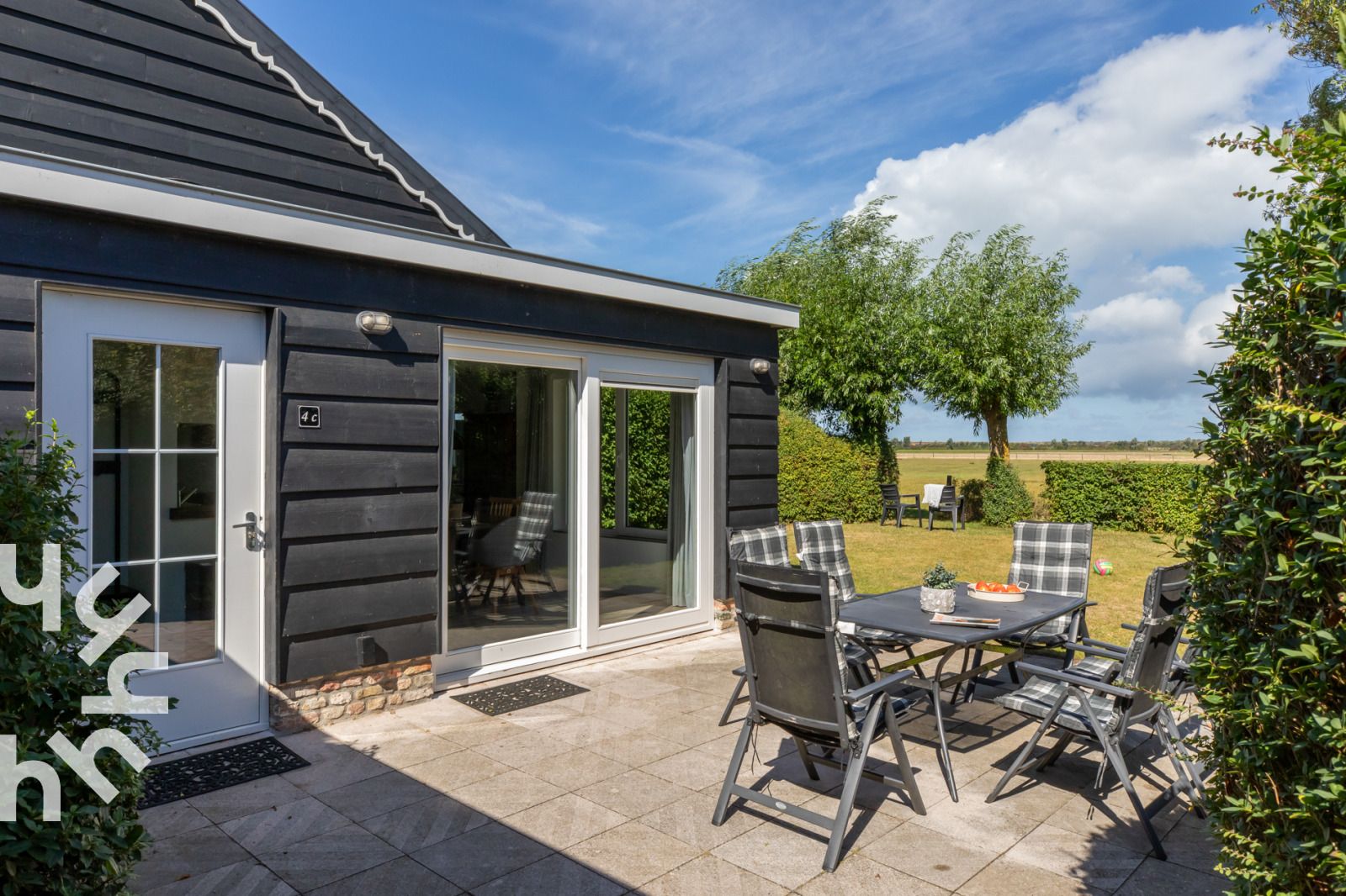 Terrasse des Ferienhauses ZE257 in Aagtekerke, Walcheren, Zeeland mit Blick auf einen gruenen Garten.