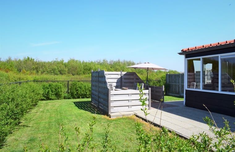 Terrasse des Ferienhauses in Zoutelande, umgeben von viel Gruen, ideal fuer Entspannung in Walcheren, Zeeland.