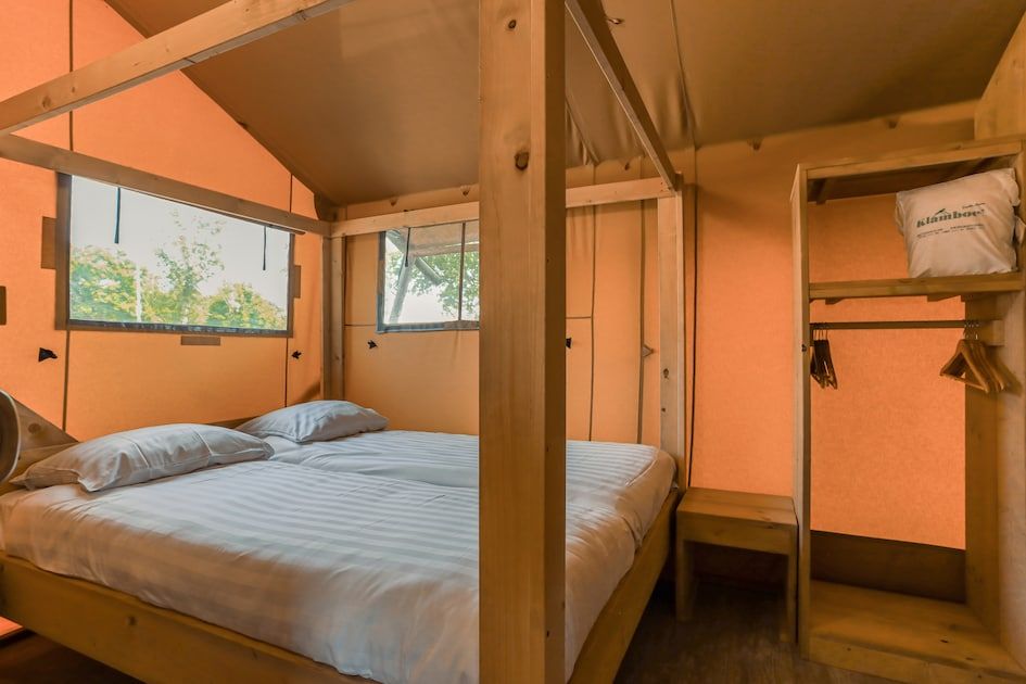 Gemuetliches Schlafquartier im Safari-Zelt 8, einer Glamping-Lodge in Vrouwenpolder, Walcheren, Zeeland mit Etagenbetten und Holzinterieur.