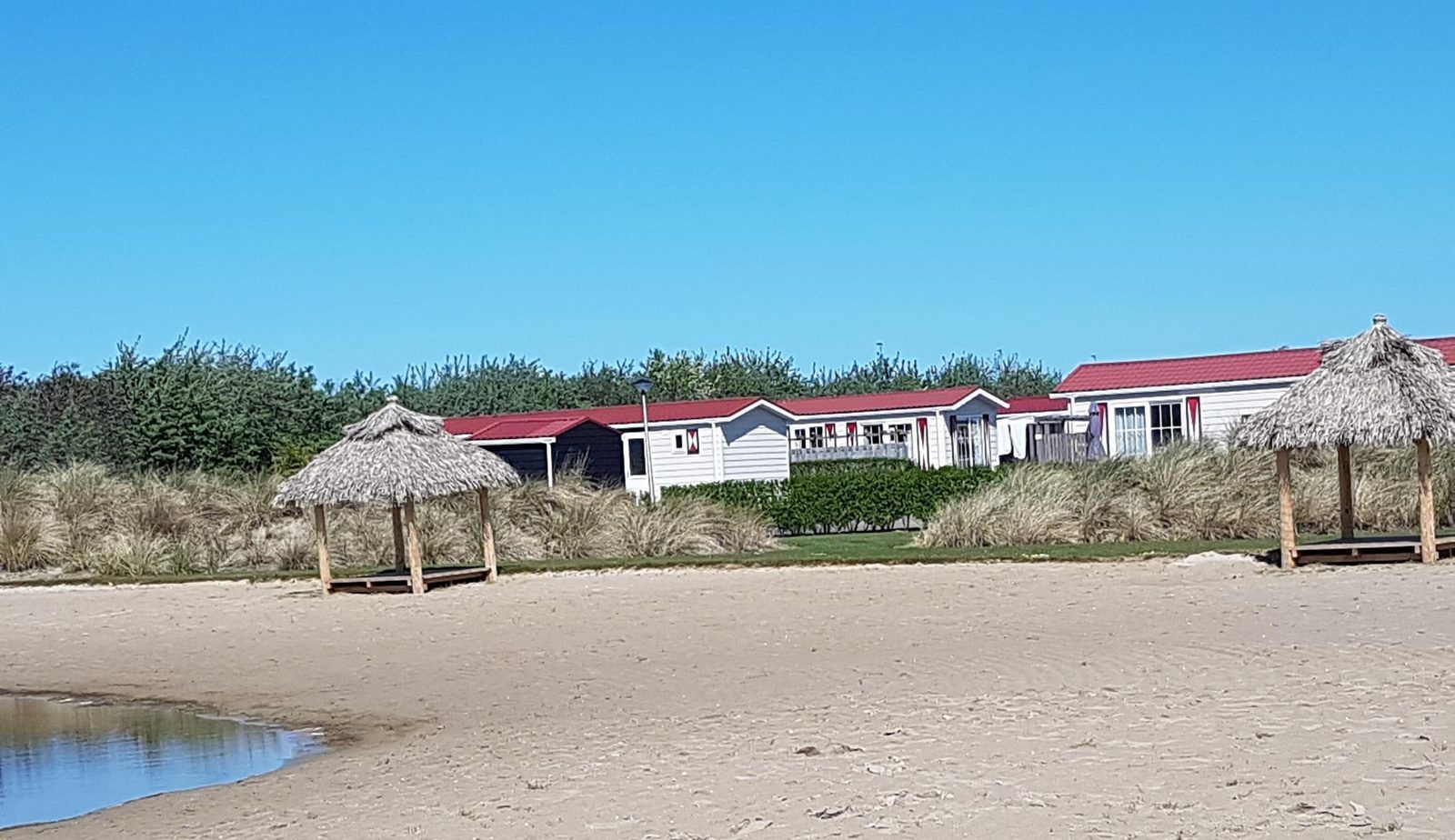 Beach view at VZ824 Chalet in Veere, Serooskerke, Walcheren, with thatched umbrellas and dunes.