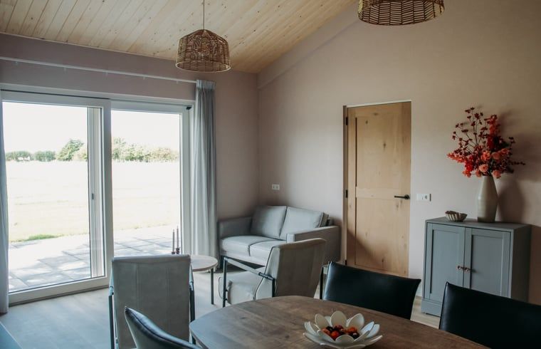 Ruime woonkamer met terraszicht in Vakantiehuis in Ritthem, Walcheren, Zeeland.