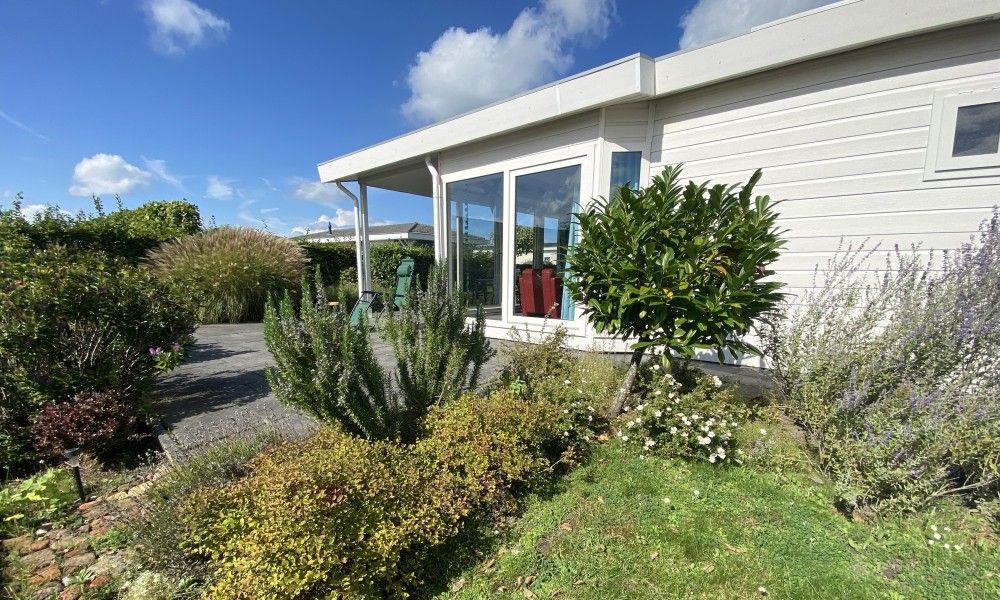 Buitenkant van Casa Mari chalet in Breskens, Zeeuws-Vlaanderen, omgeven door natuur en een uitnodigend terras voor ontspanning.