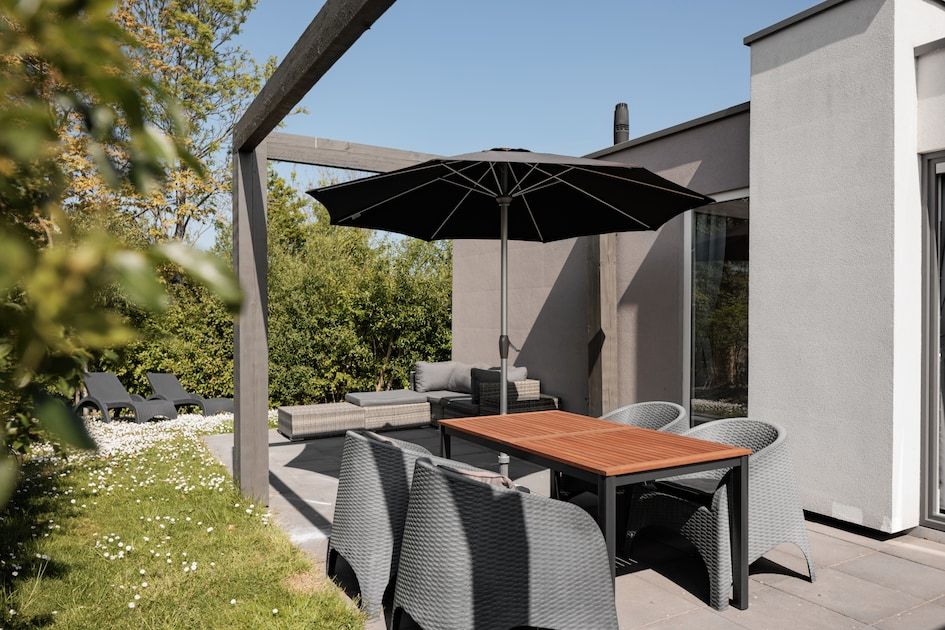 Ruim terras van Lodge 4B in Breskens, Zeeland, met zitgelegenheid en parasol voor ontspannen buitenleven.