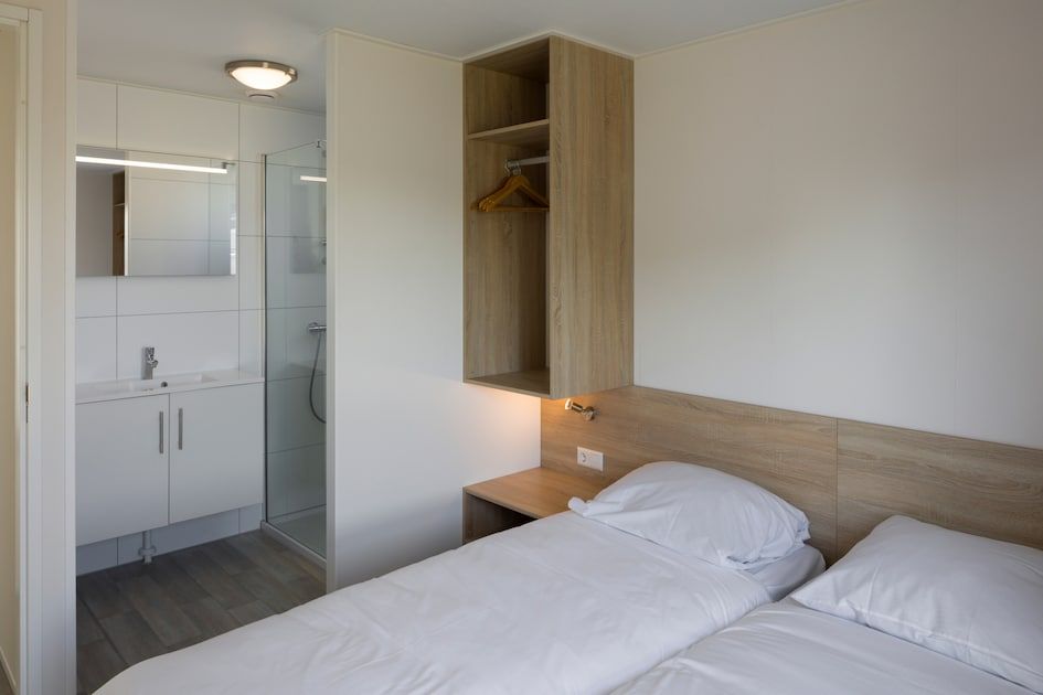 Sfeervolle slaapkamer in L4A Comfort vakantiehuis, Nieuwvliet-Bad, Zeeland, met comfortabele bedden en moderne badkamer.