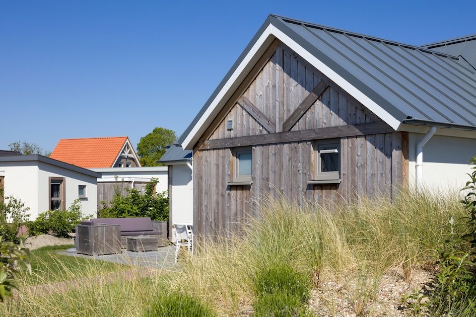 L6B Komfort-Ferienhaus in Nieuwvliet-Bad, Zeeland mit Holzfassade und Terrasse, umgeben von Duenen und Natur.