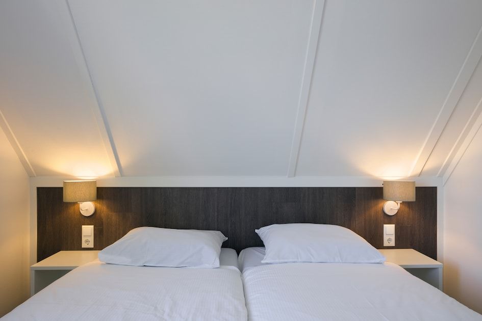 Komfortables Schlafzimmer im V8 Luxus-Ferienhaus in Nieuwvliet-Bad, Zeeland, mit stimmungsvoller Beleuchtung.