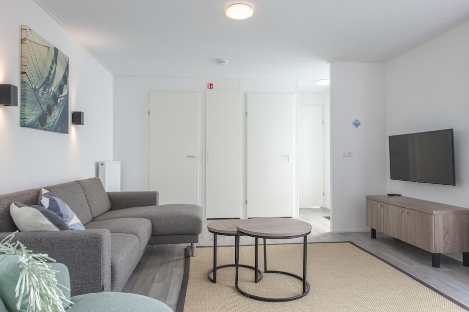 Modernes Wohnzimmer im Ferienhaus L4 Comfort in Nieuwvliet-Bad, Zeeuws-Vlaanderen, Zeeland mit gemuetlicher Sitzecke und TV.