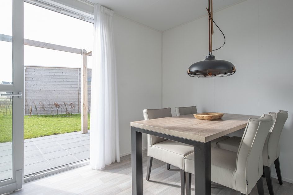 Stilvolles Esszimmer im Ferienhaus L4 Comfort, Nieuwvliet-Bad, mit Blick auf die Terrasse und den gruenen Garten in Zeeuws-Vlaanderen, Zeeland.