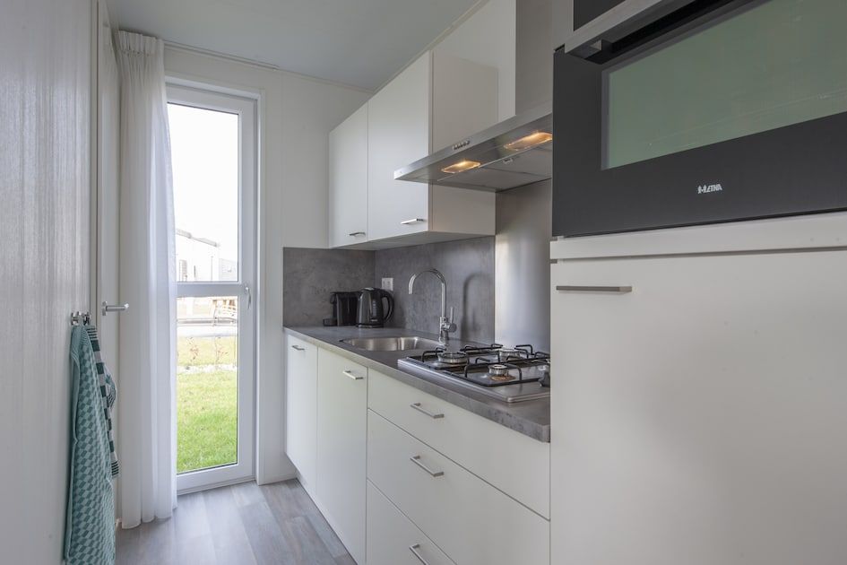 Moderne Kueche im Ferienhaus L4 Comfort, Nieuwvliet-Bad, Zeeuws-Vlaanderen mit Blick auf die gruene Umgebung.