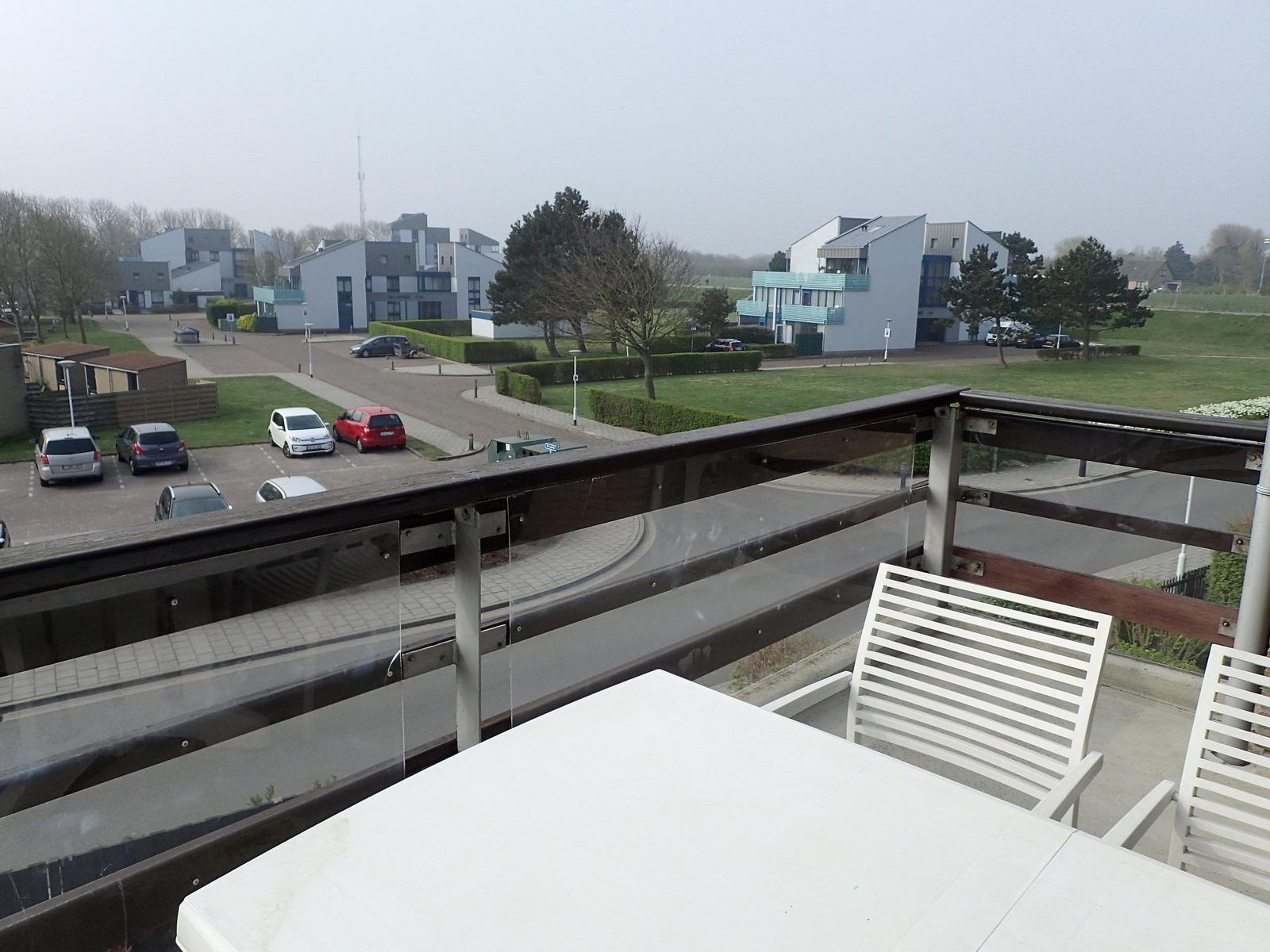 Blick vom Balkon der Ferienwohnung VZ922 in Cadzand, mit Blick auf moderne Architektur und gruene Umgebung in Zeeland.