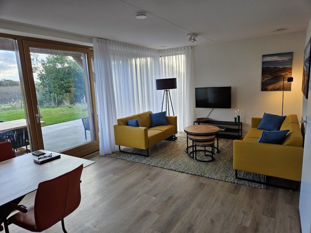 Gezellige woonkamer van Vrijstaande woning in Cadzand, Zeeuws-Vlaanderen, met uitzicht op terras en natuur.